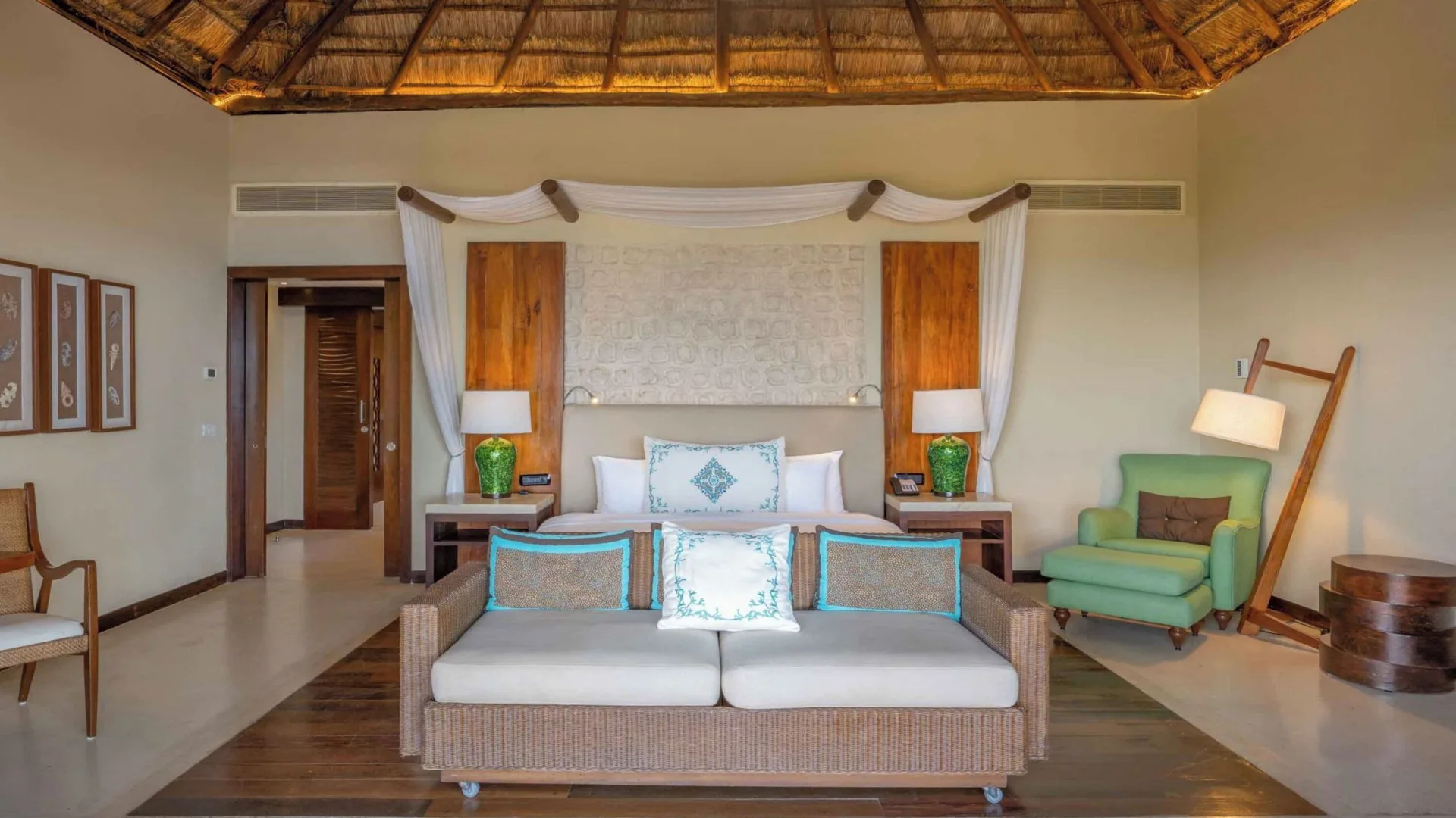 Premium Villa king bed and sitting area beneath a thatched ceiling at Viceroy Riviera Maya.