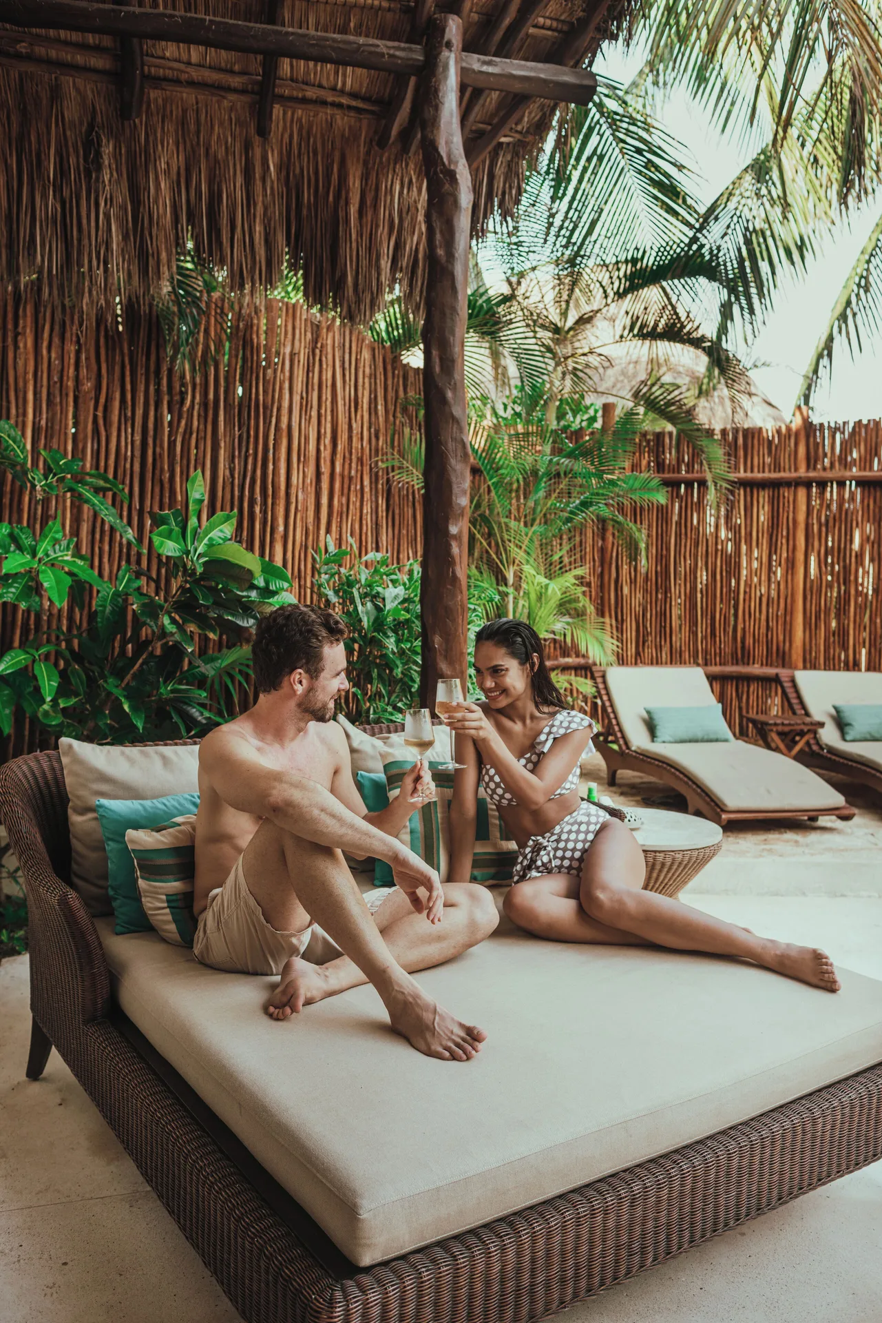 Couple on an outdoor villa daybed with lounge chairs at Viceroy Riviera Maya.