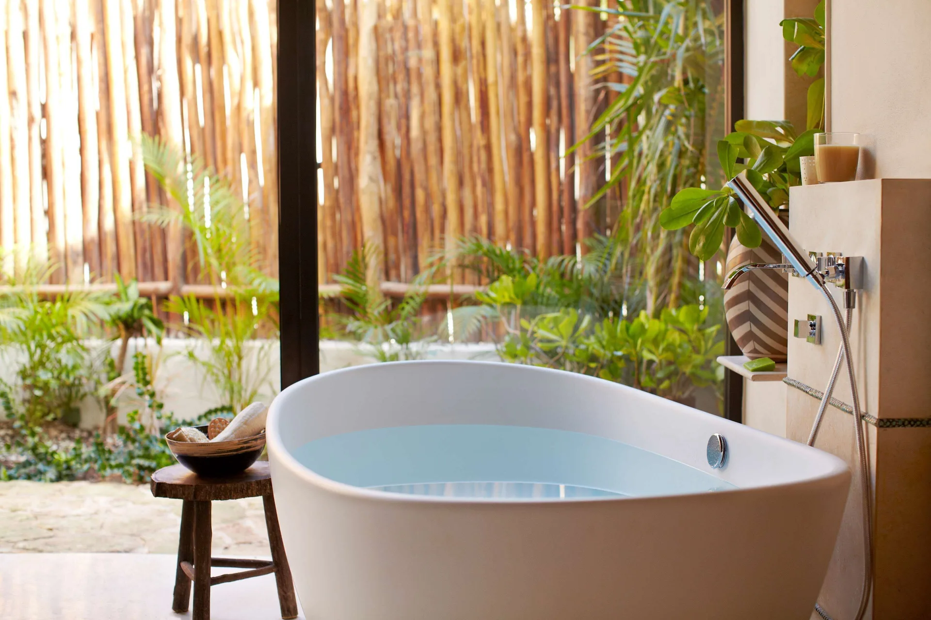 Close-up of a villa soaking tub beside garden-facing glass at Viceroy Riviera Maya.