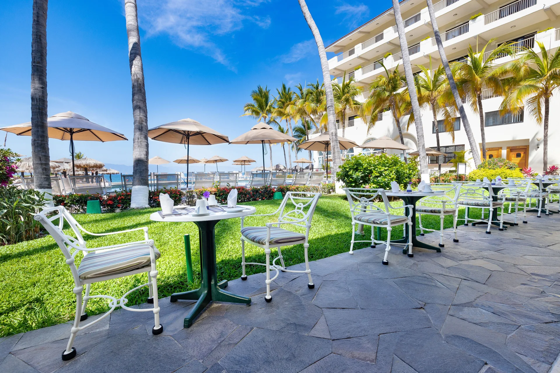 Garden dining tables near palms and balconies at Villa del Palmar Beach Resort and Spa, Puerto Vallarta.