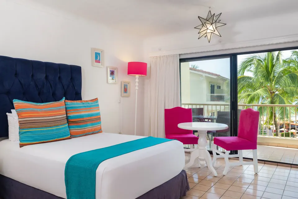 Junior Suite king bed beside balcony doors and a small dining table at Villa del Palmar Beach Resort and Spa, Puerto Vallarta