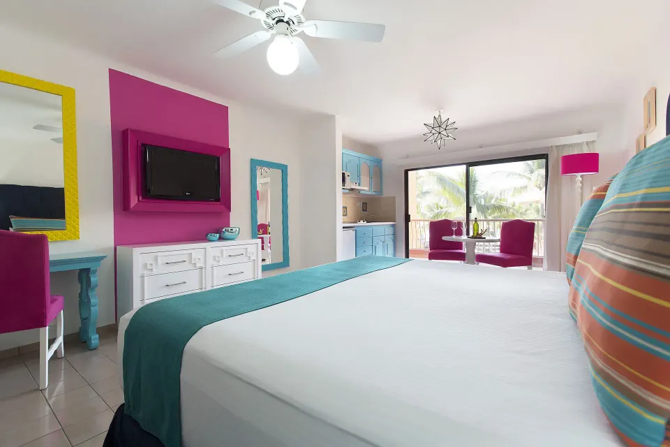 Junior Suite king bed facing TV, kitchenette, and balcony at Villa del Palmar Beach Resort and Spa, Puerto Vallarta.