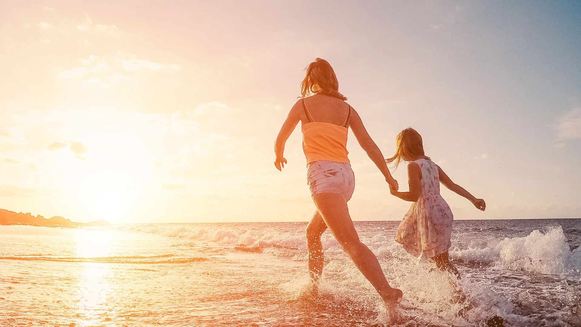 Two children running through surf at sunset at Villa del Palmar Cancun Beach Resort & Spa.