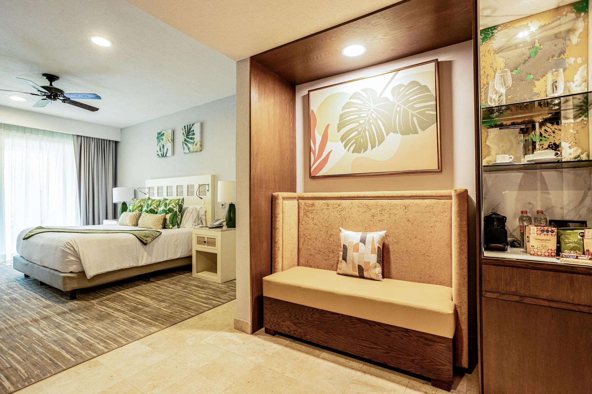 Deluxe room entry with bed, bench, and refreshment cabinet at Villa del Palmar Cancun Beach Resort & Spa.