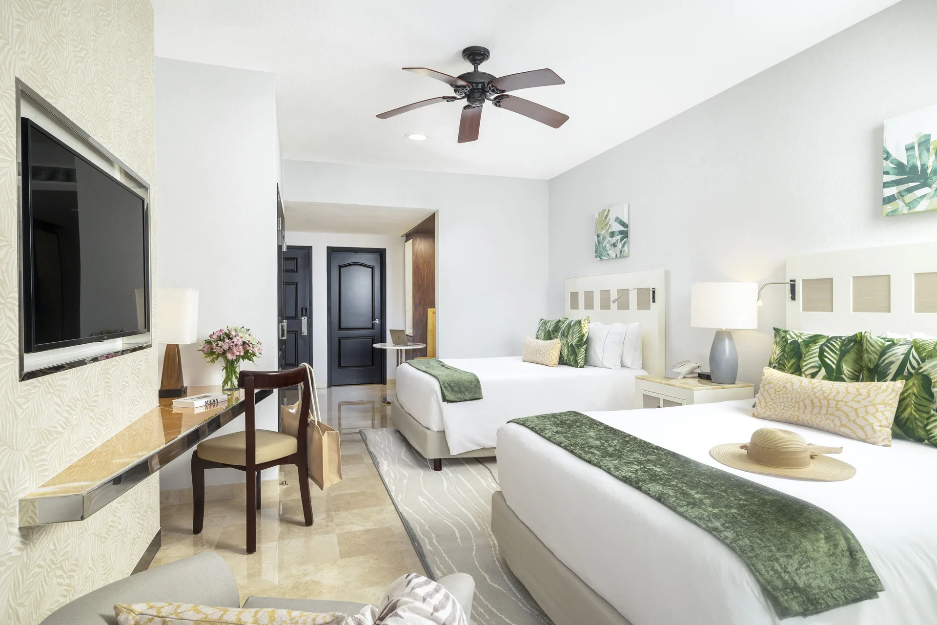 Deluxe room with two beds, desk, and wall-mounted TV at Villa del Palmar Cancun Beach Resort & Spa.