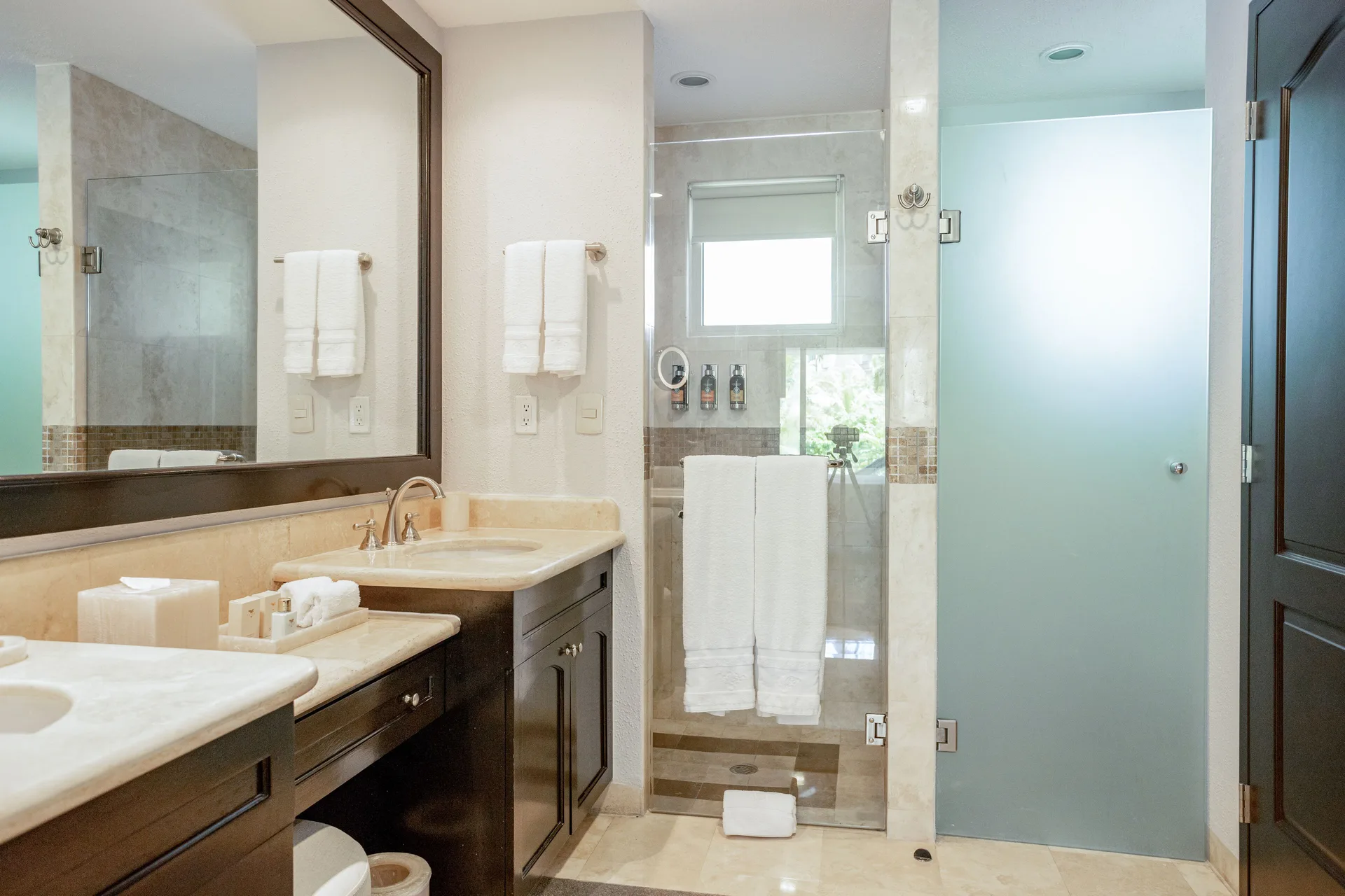 One Bedroom bathroom with vanity, shower, and frosted glass door at Villa del Palmar Cancun Beach Resort & Spa.