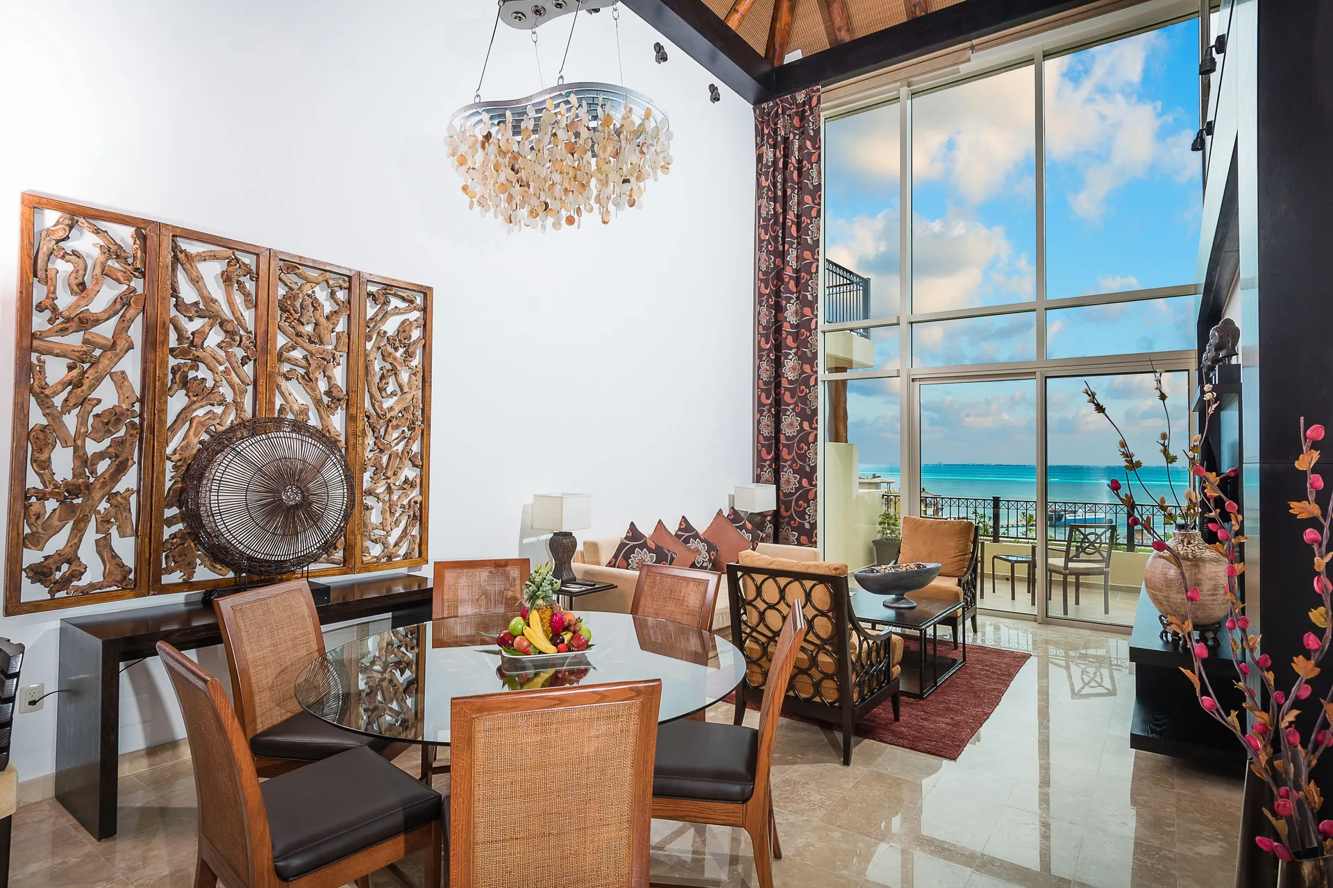 Two Bedroom Loft dining and living area with ocean-facing windows at Villa del Palmar Cancun Beach Resort & Spa.