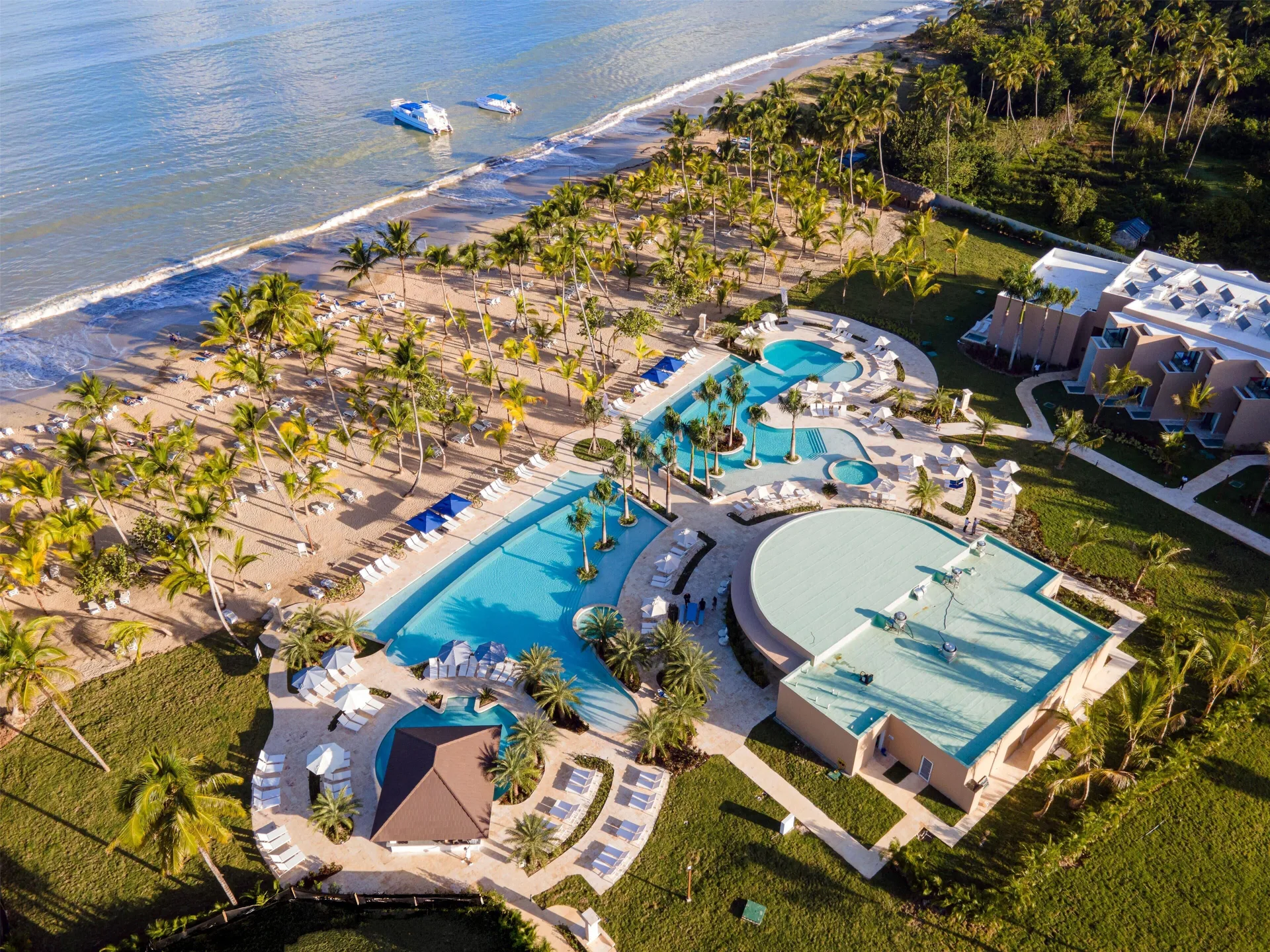 Aerial view of the beachfront, pools, palms, and boats offshore at Viva Miches.