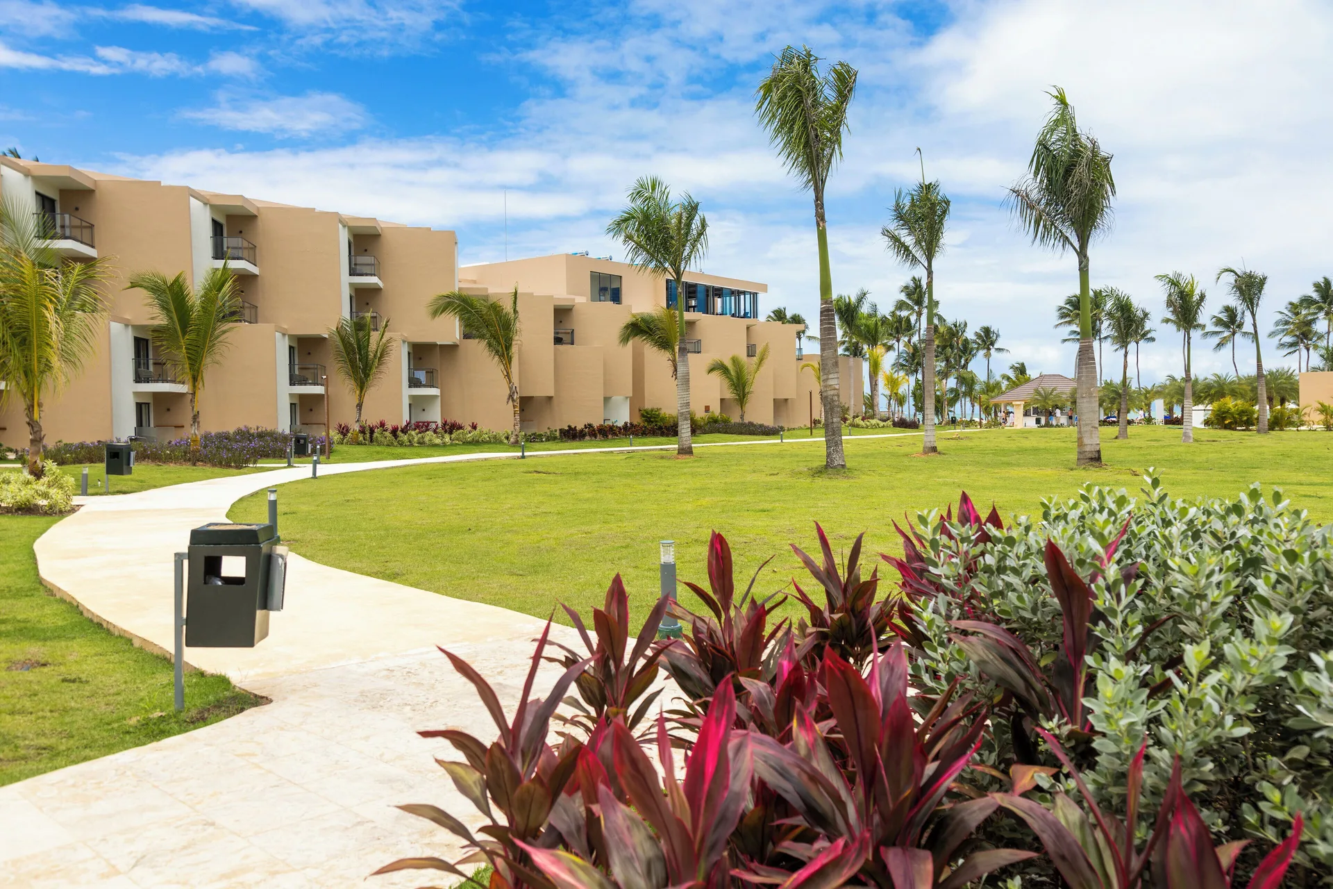 Curving garden walkway with palms and guestroom buildings at Viva Miches.
