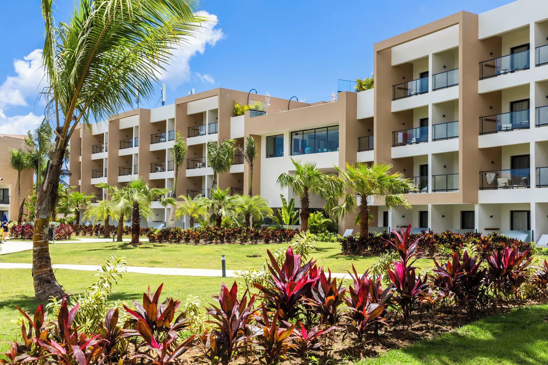 Guestroom buildings and tropical landscaping at Viva Miches under a blue sky.