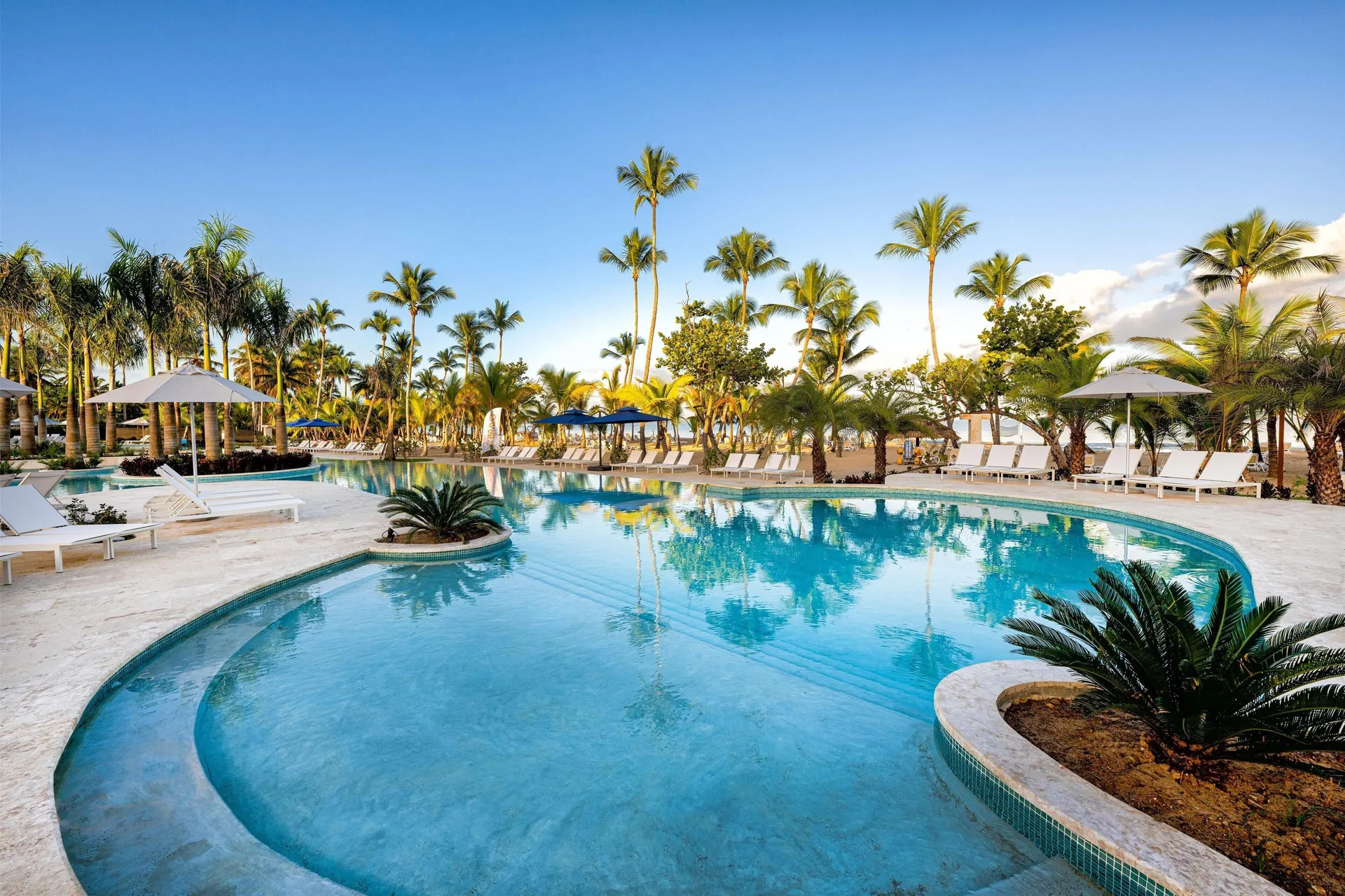 Lagoon-style pool reflecting palm trees beside the beach at Viva Miches.