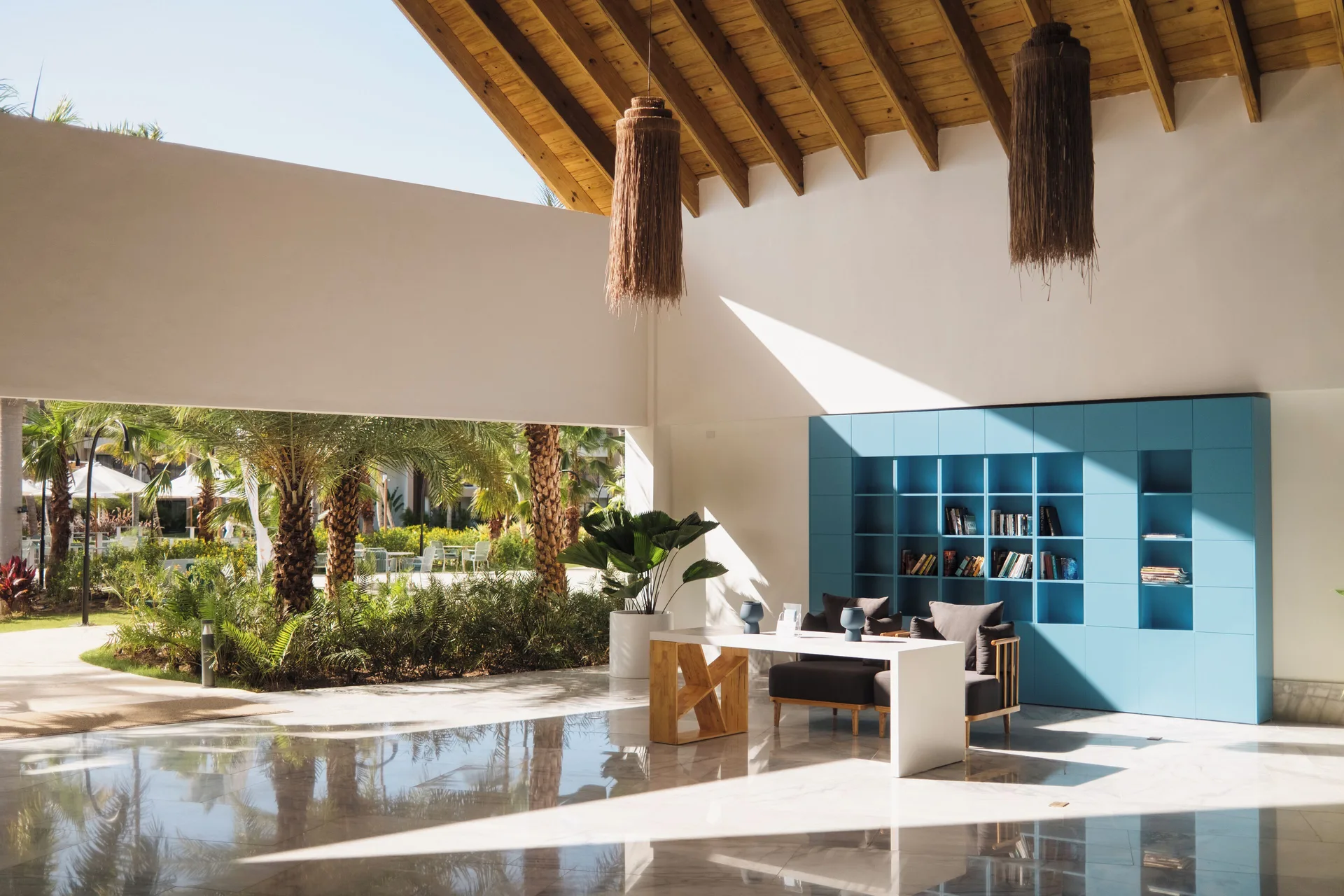 Quiet lobby nook with blue shelving and garden views at Viva Miches.