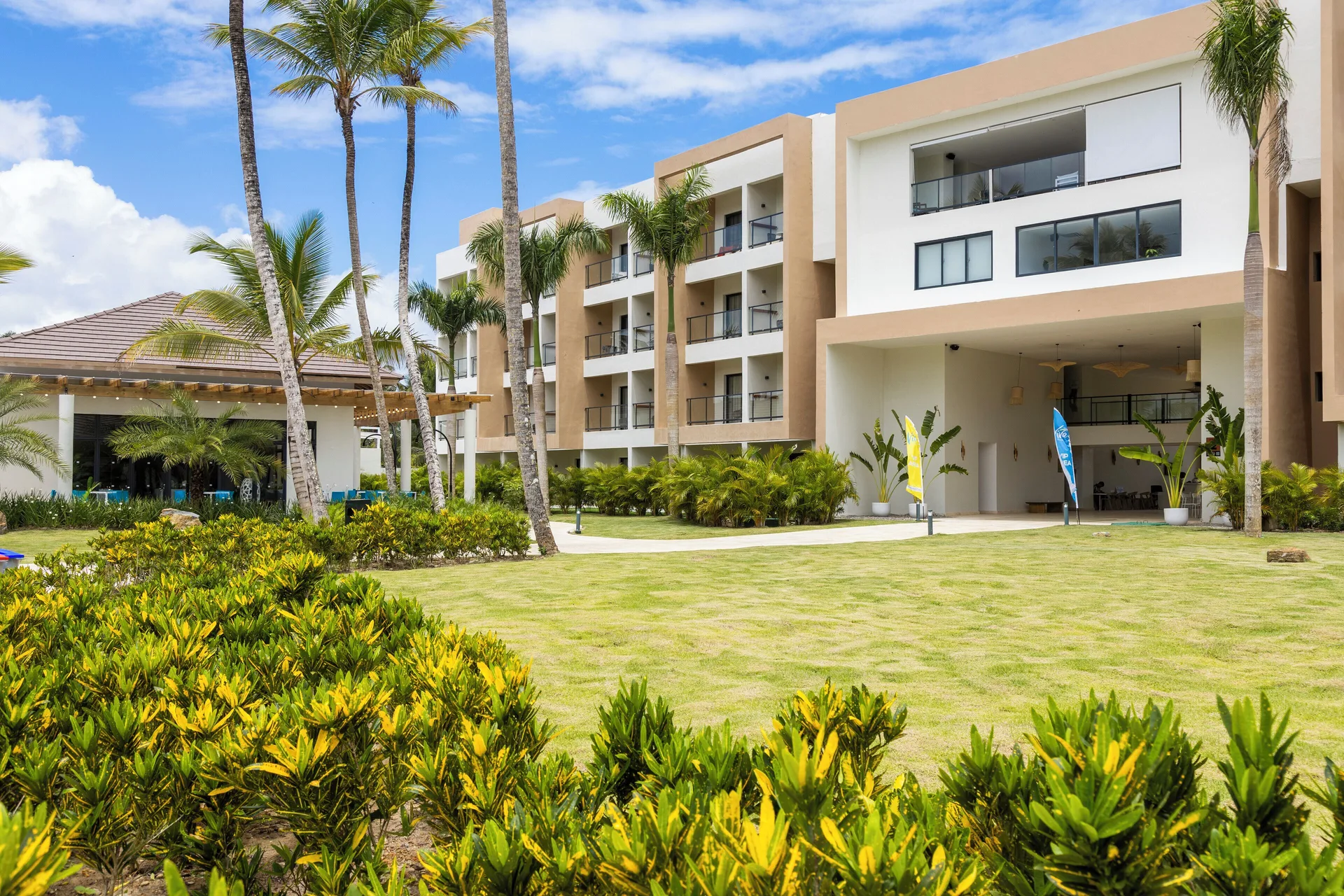 Lawn, palms, and modern resort building exterior at Viva Miches.