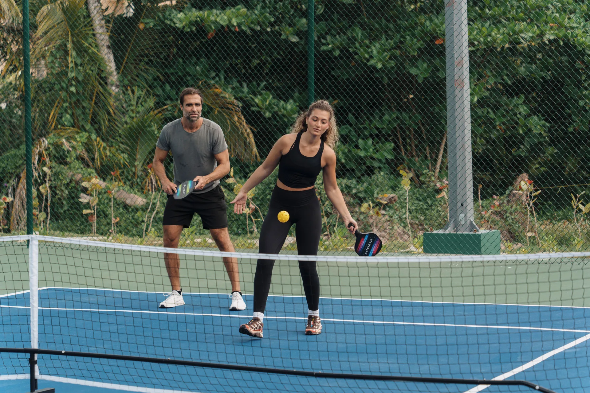 Two guests playing pickleball on an outdoor court at Viva Miches.