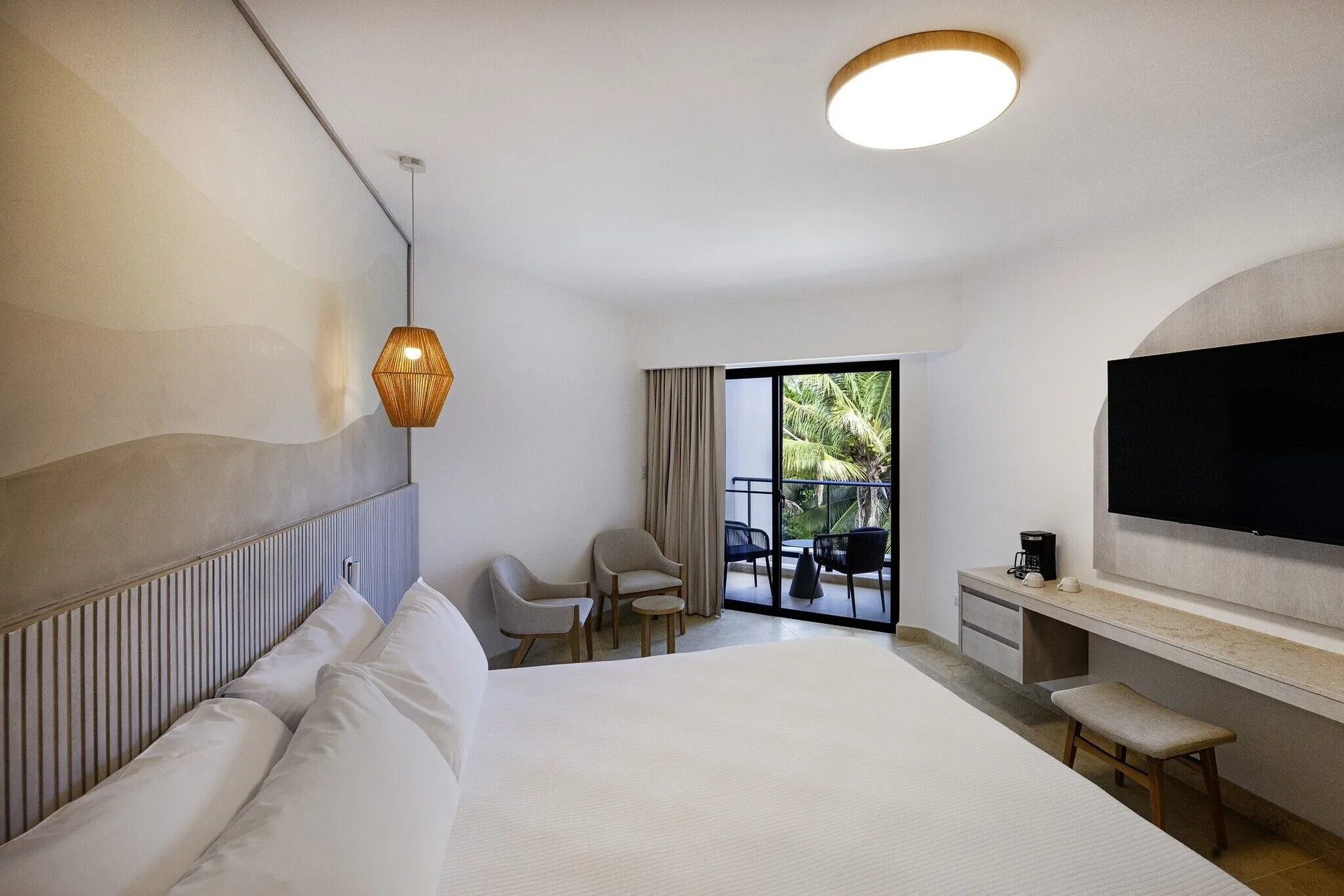 Splash Room king bed facing a balcony, TV wall, desk, and chairs at Viva Miches.