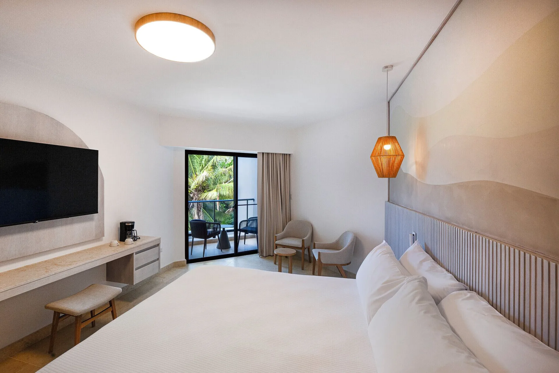 Splash Room king bed with TV, desk, seating area, and balcony at Viva Miches.