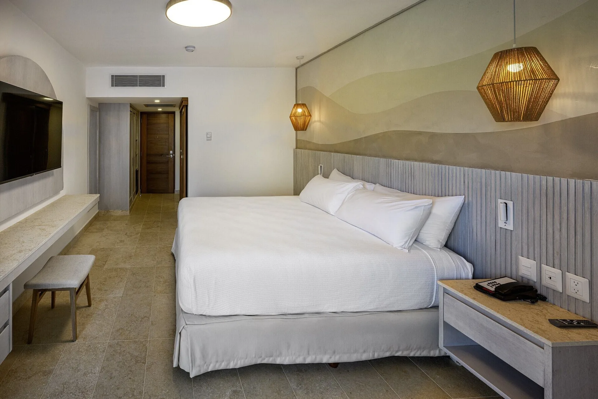 Splash Room king bed with bedside table, TV wall, and entry door at Viva Miches.