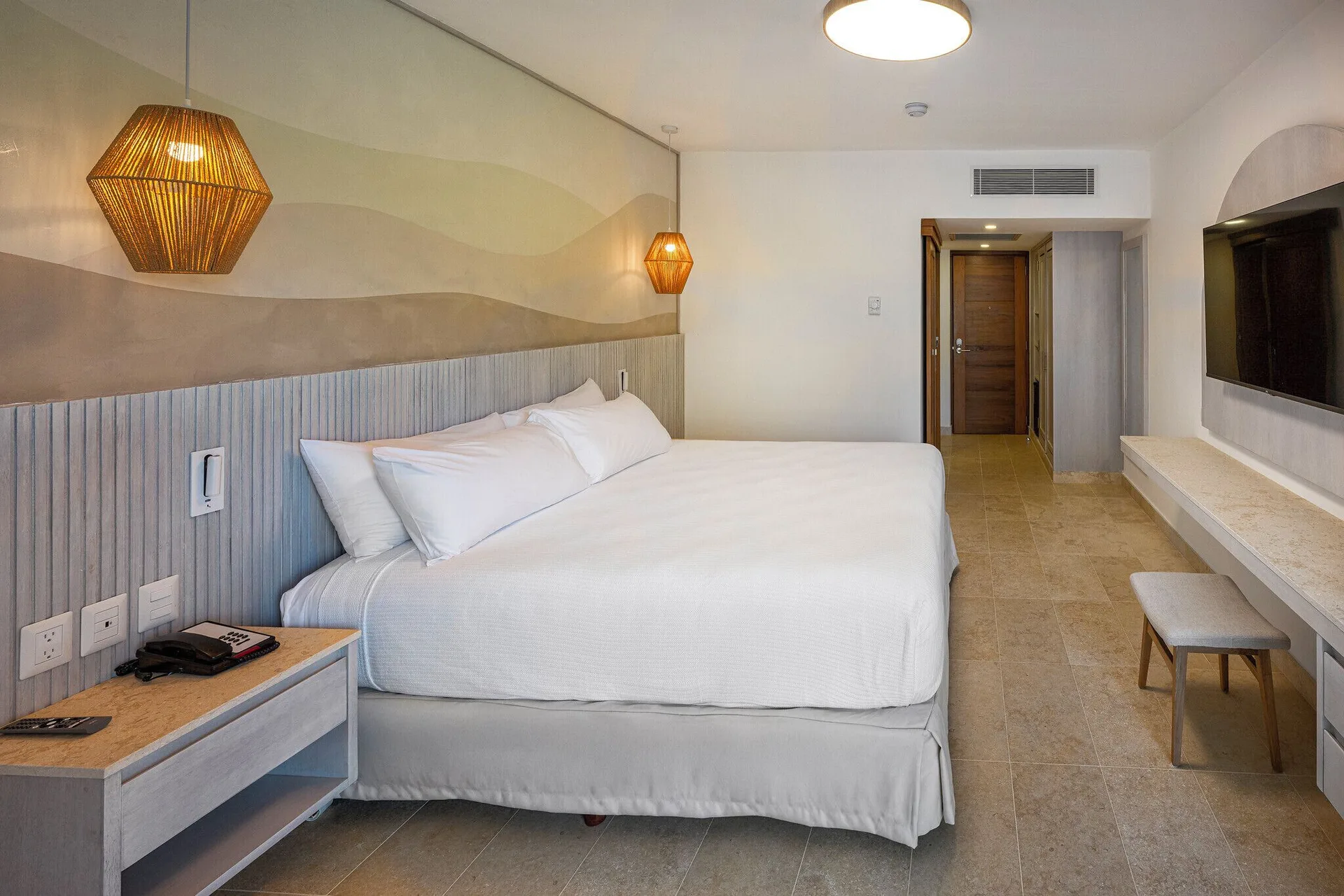 Splash Room king bed with pendant lights and TV wall at Viva Miches.