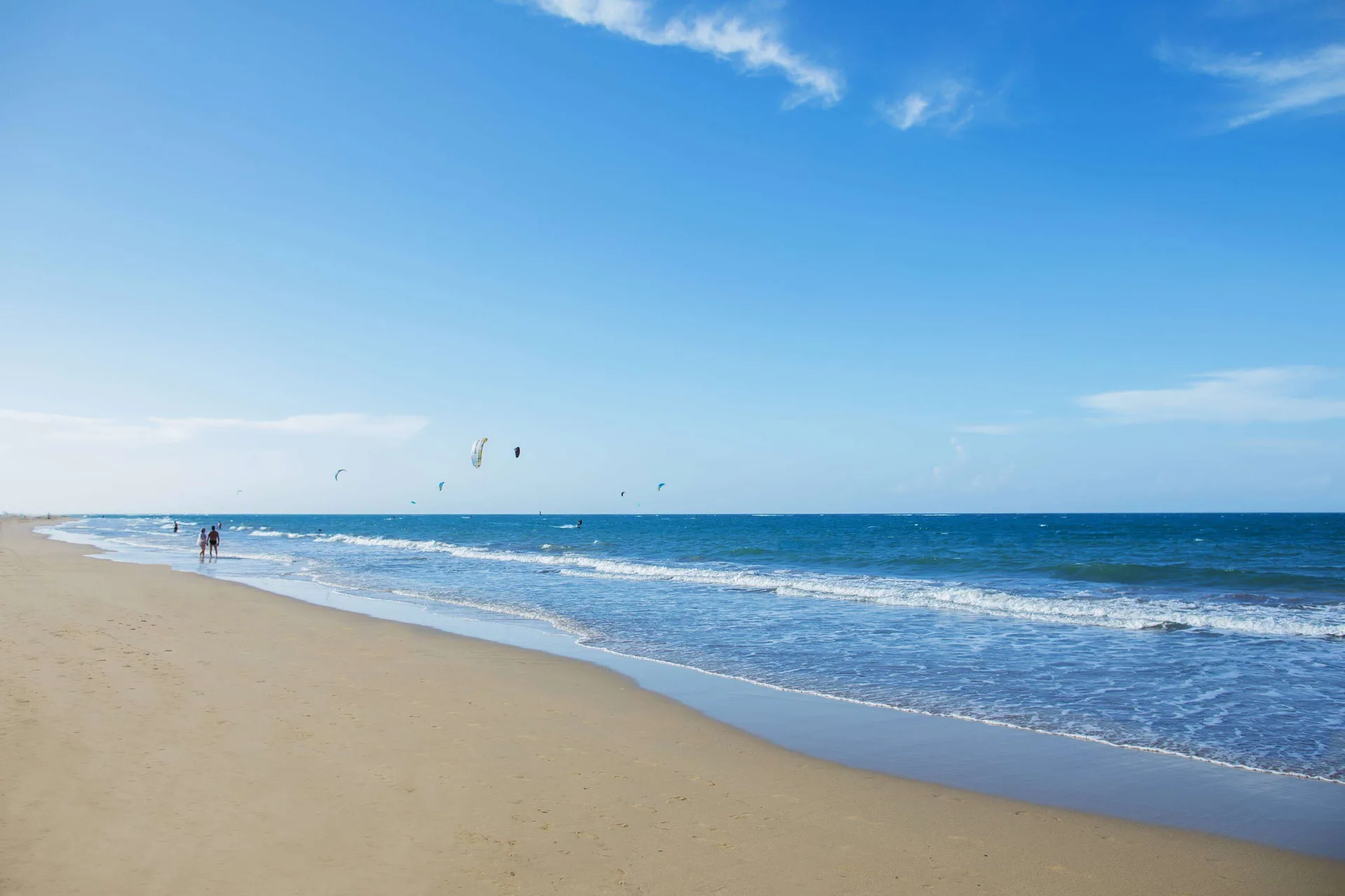 Open beach with small waves and kitesurfers offshore at Viva Tangerine.