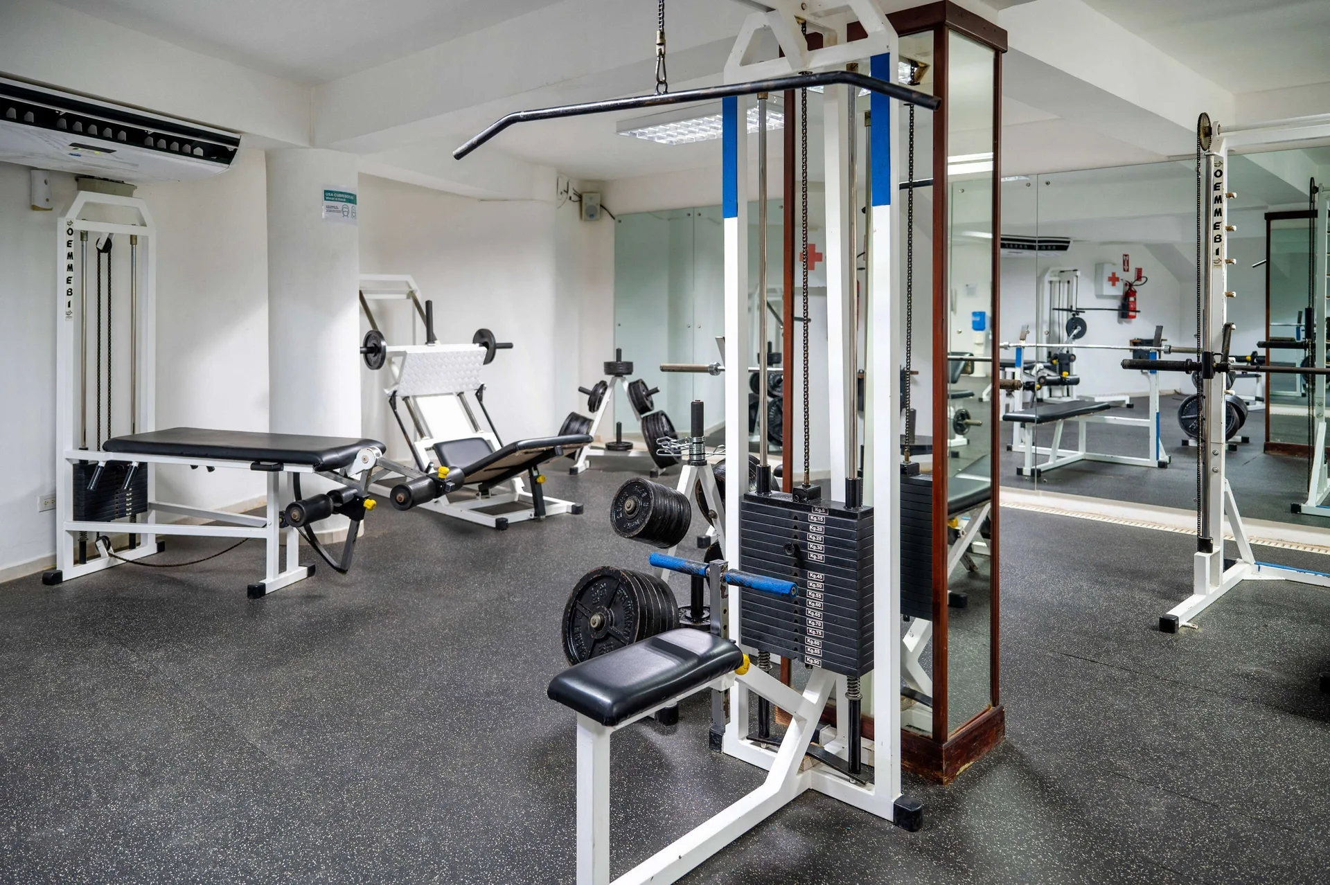 Fitness room with weight machines, benches, mirrors, and rubber flooring at Viva Tangerine.