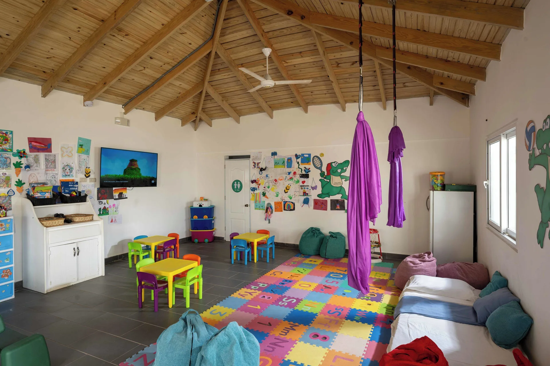 A colorful kids club room with play tables and hanging fabric at Viva Tangerine.