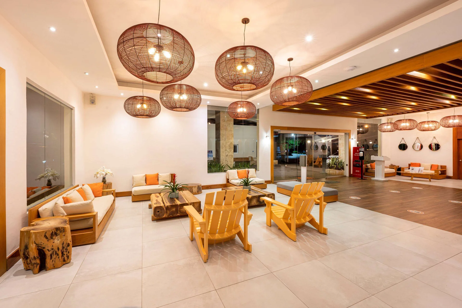 Lobby lounge with woven pendant lights, sofas, and wooden chairs at Viva Tangerine.