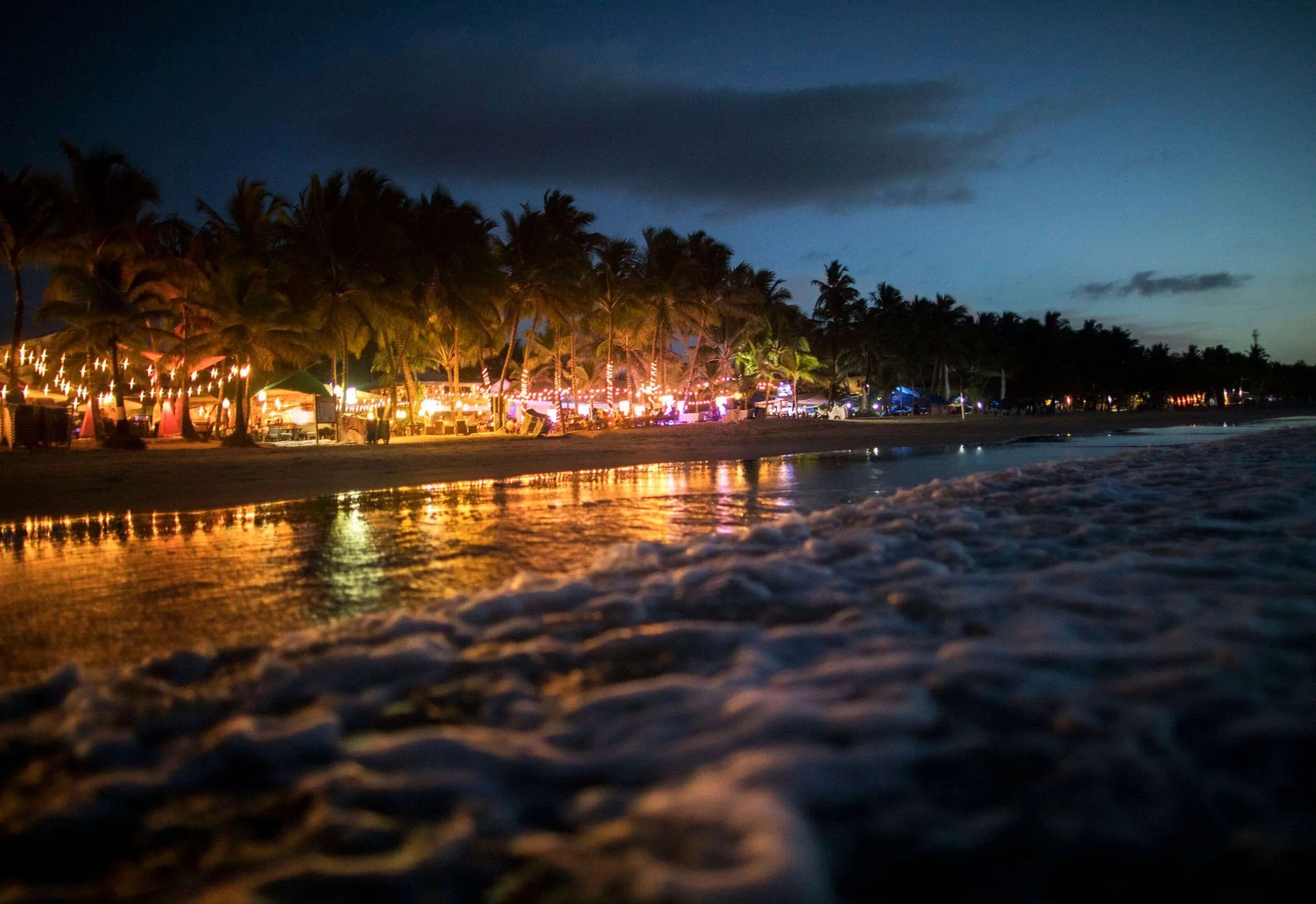 Nighttime beach scene with lights along the shore at Viva Tangerine.