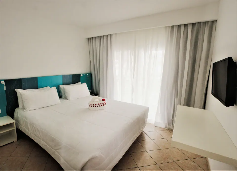 Superior Garden room with king bed, teal headboard, TV, and sheer curtains at Viva Tangerine.