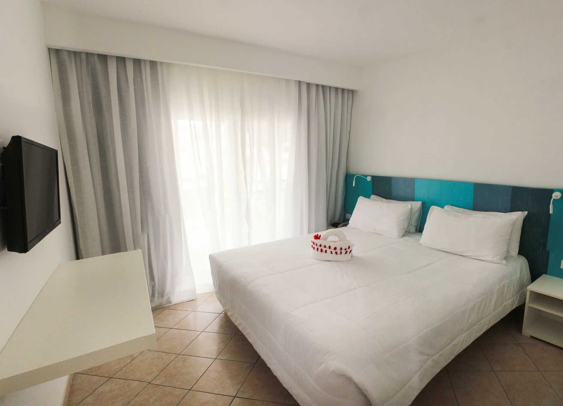 Superior Garden room with king bed, wall TV, and curtained balcony light at Viva Tangerine.