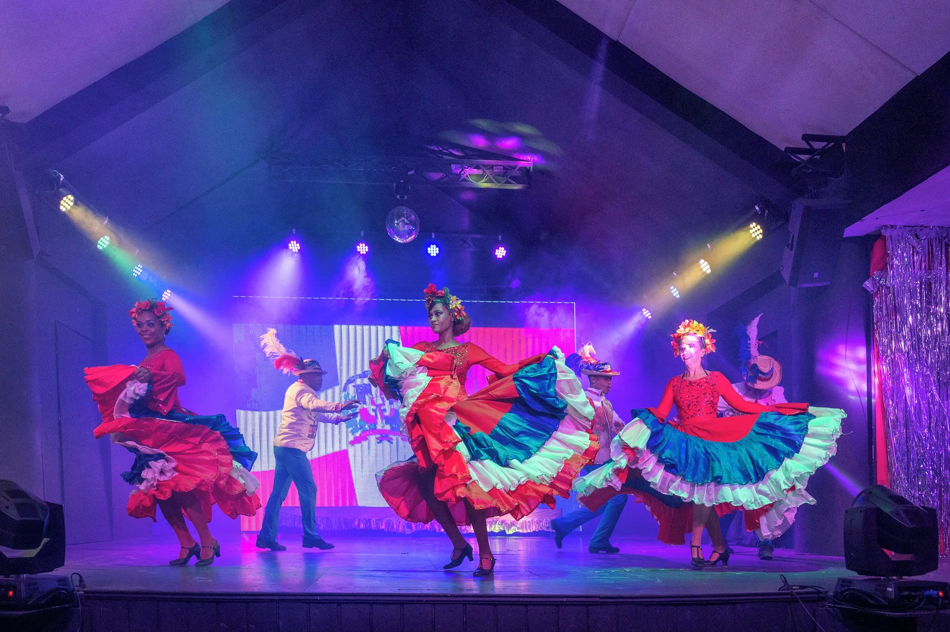 Dancers in colorful skirts perform under stage lights at Viva Tangerine.