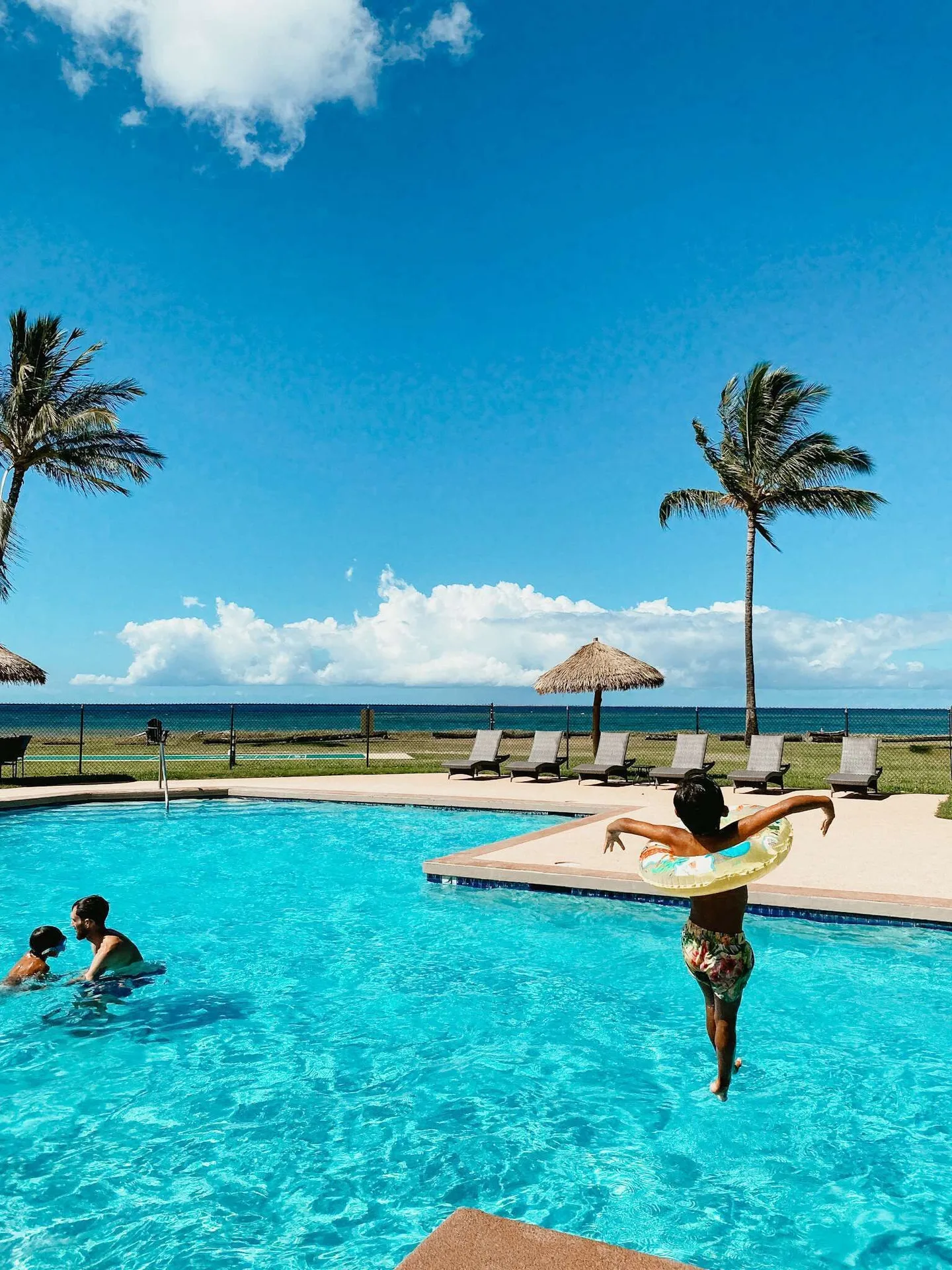 Guests swimming and jumping into the oceanfront pool at Waimea Plantation Cottages.