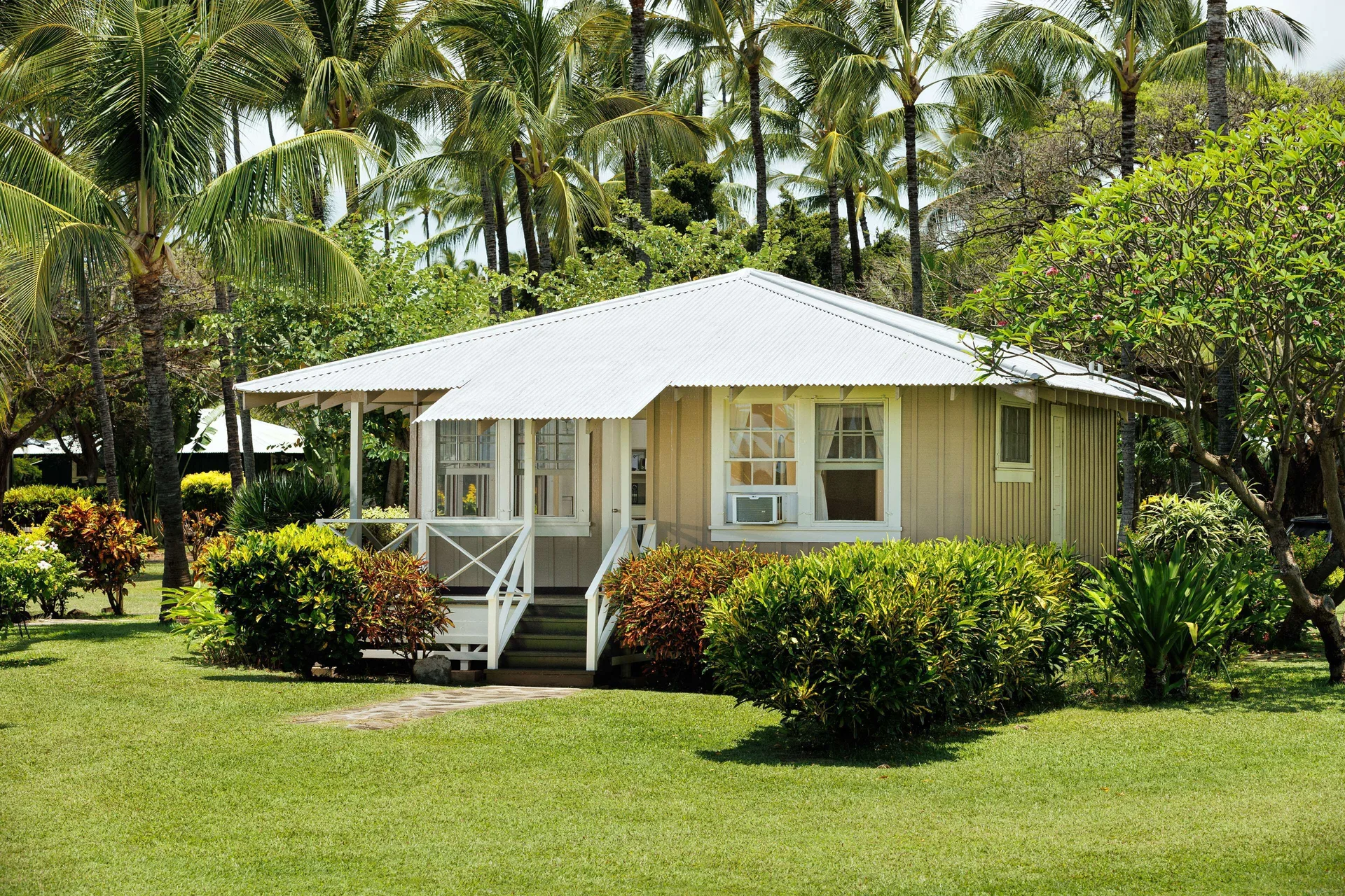 Coast Cottage exterior amid palms and lawn at Waimea Plantation Cottages.