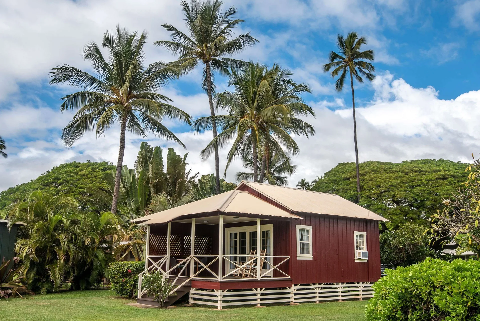 Coast Cottage exterior with porch and palms at Waimea Plantation Cottages.