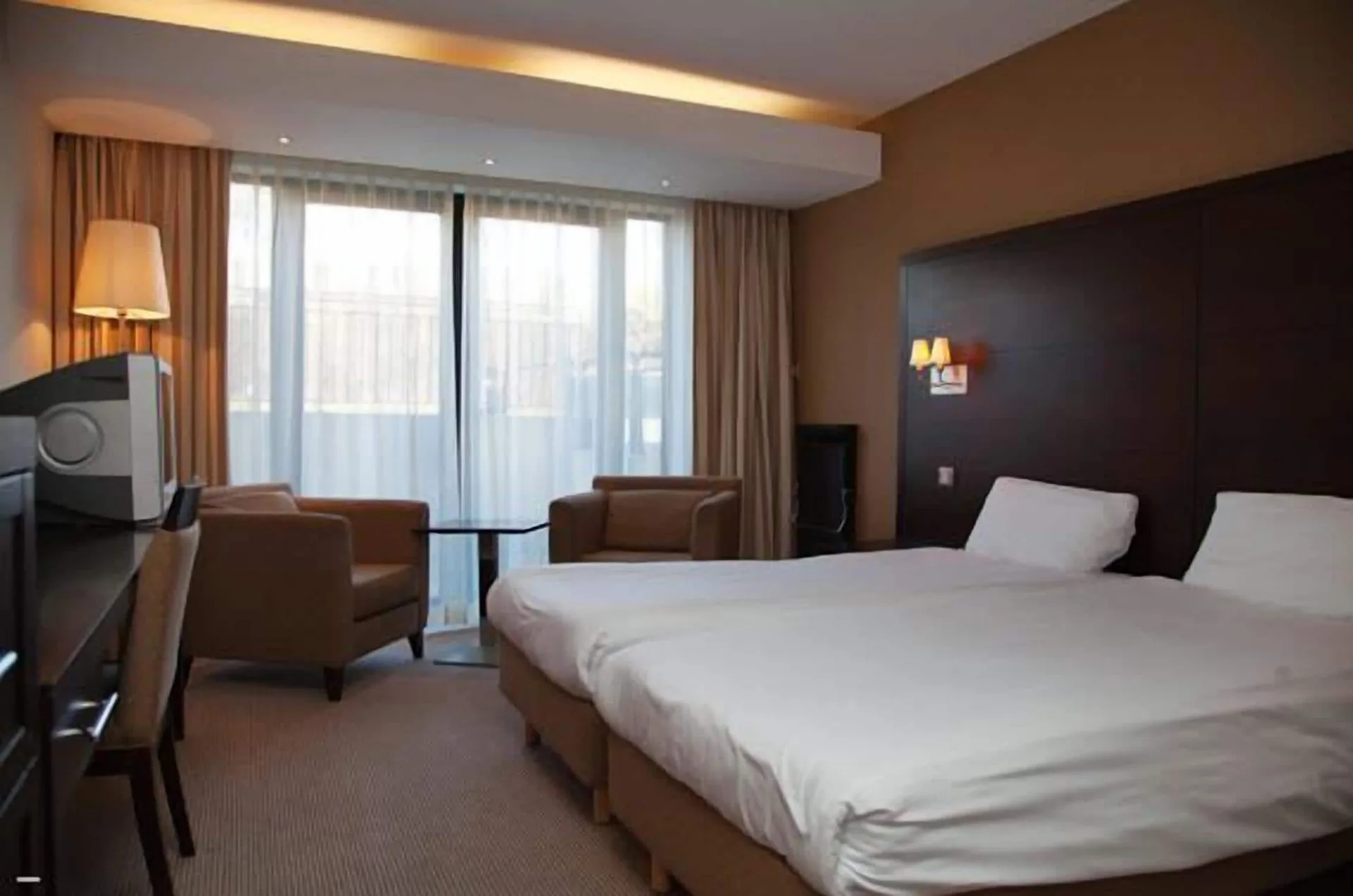 Twin-bed guest room with seating by the window at White Sands Hotel.